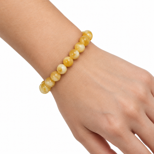 Bransoletka z zodtego kamienia na nadgarstku, biale tlo